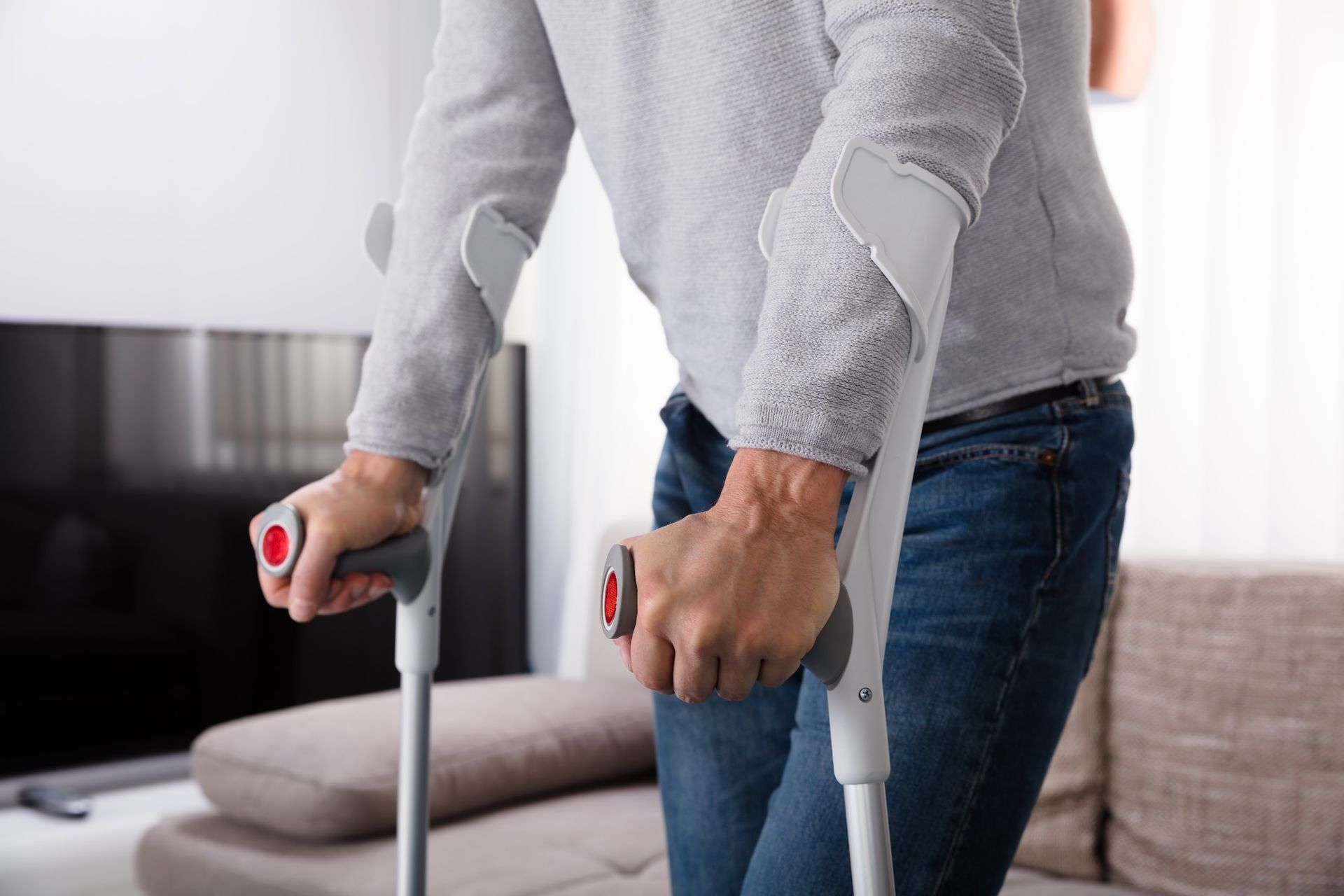 Person Using Crutches Indoors, Leaning Forward Slightly, Holding Handles — My Chiropractor Mackay City in Mackay, QLD