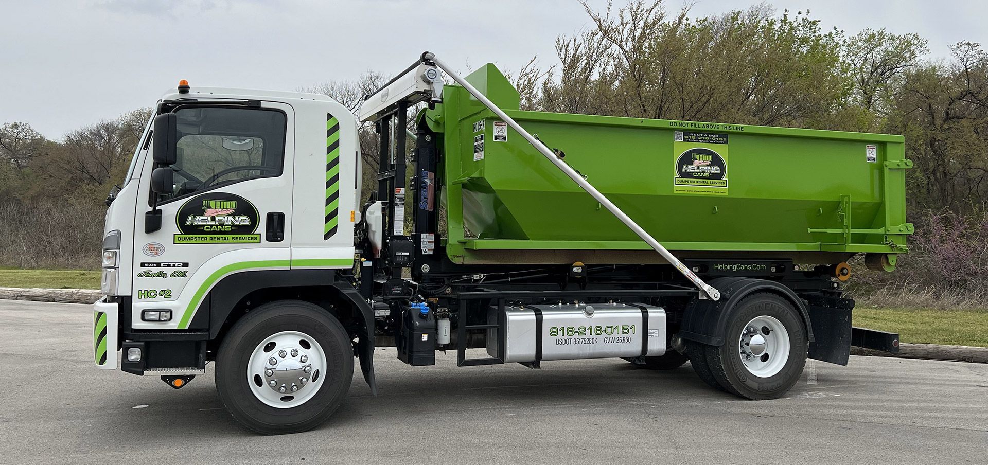 A green dump truck is parked on the side of the road.