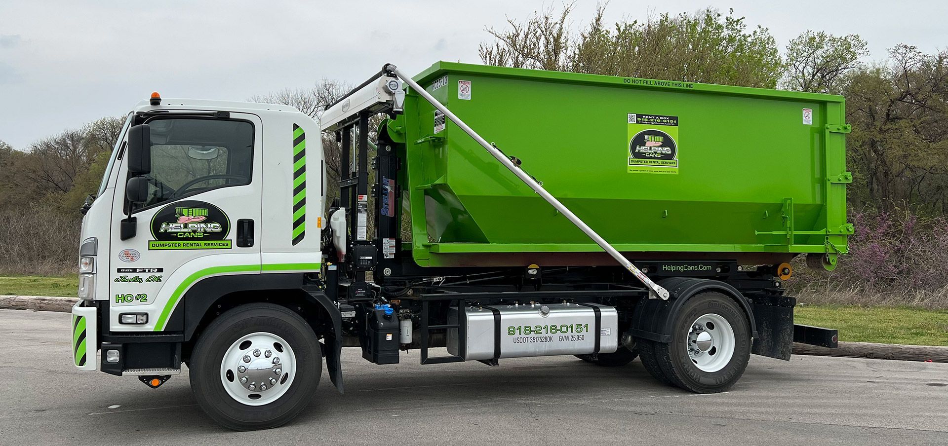 A green and white dump truck is parked in a parking lot.