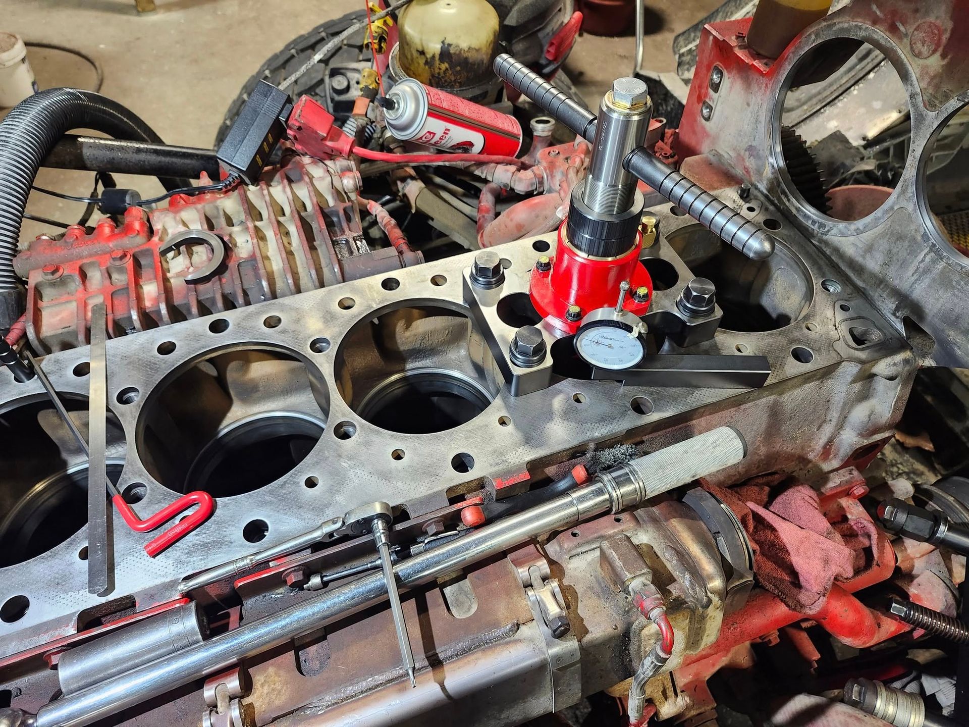 A red cylinder liner puller tool is mounted on an engine block to remove a sleeve from the cylinder bore.