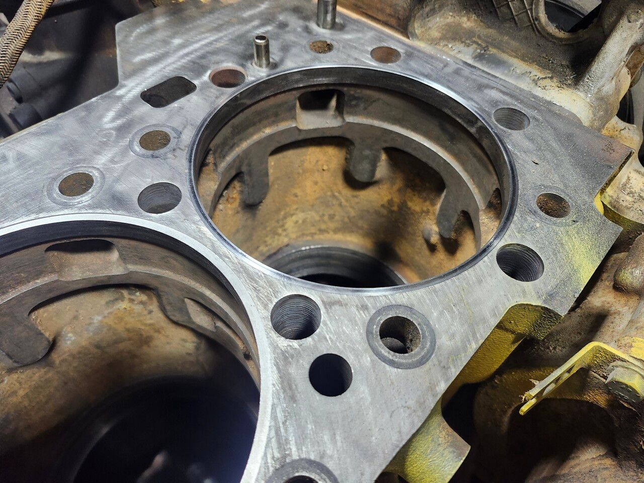Close-up of a partially disassembled engine block showing a cylinder bore, bolt holes, and metal surface texture.