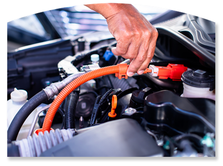 Hand holding orange jumper cable on a car battery in an open engine bay