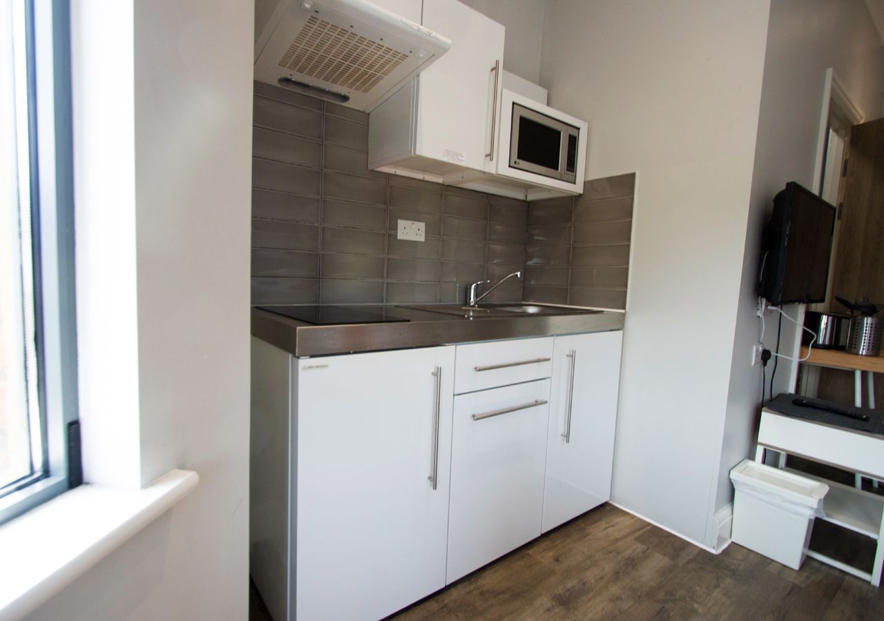 A small kitchen with white cabinets , a sink , and a microwave.