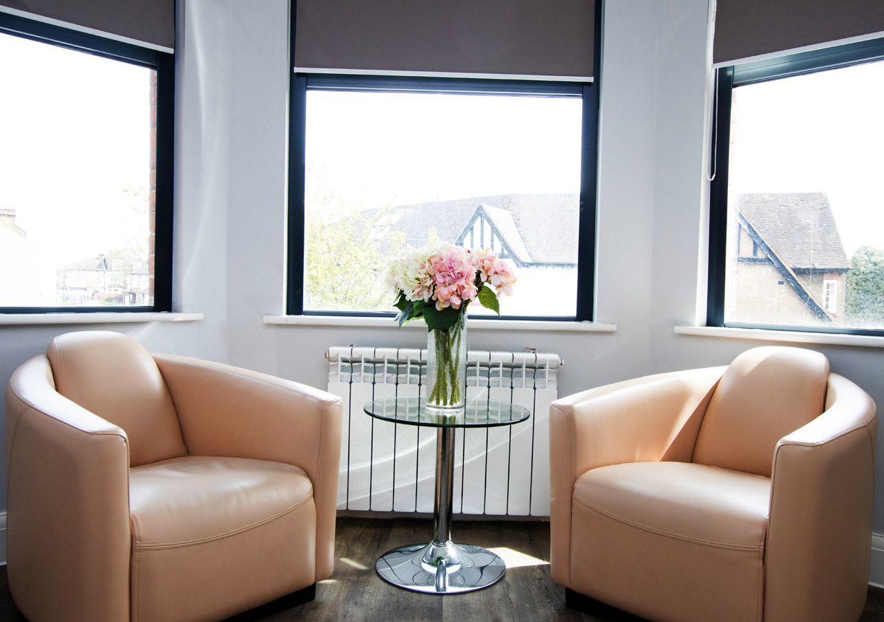 A room with two chairs and a table with a vase of flowers on it
