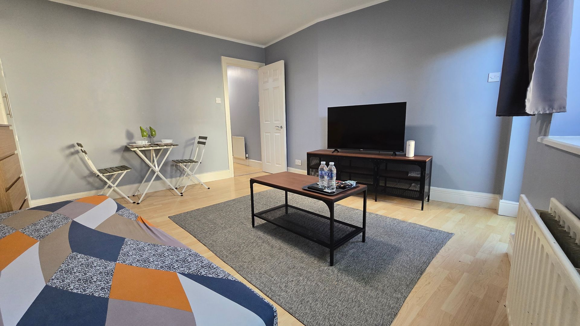 A living room with a table , chairs , and a flat screen tv.