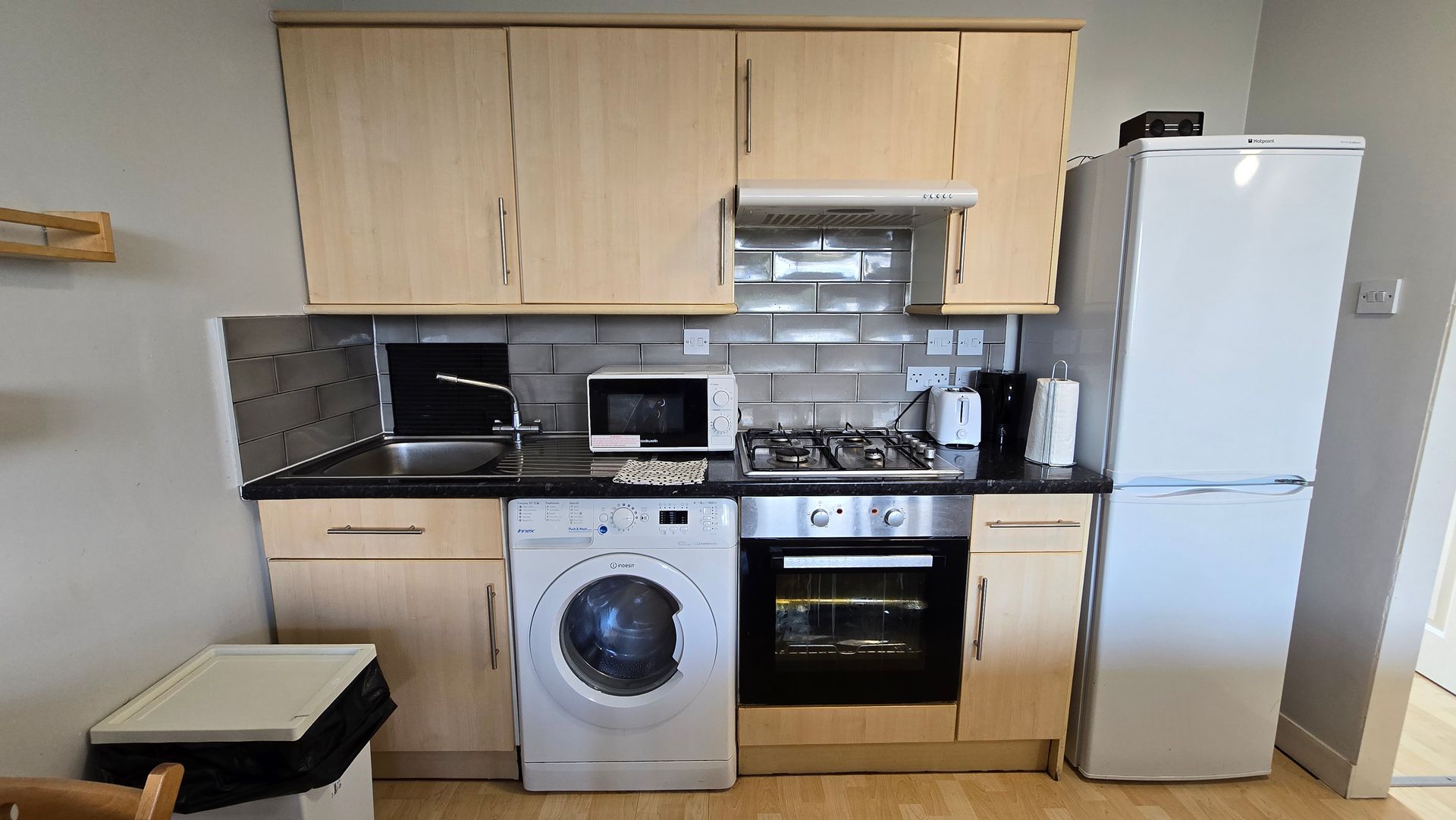 A kitchen with a washing machine , stove , refrigerator and microwave