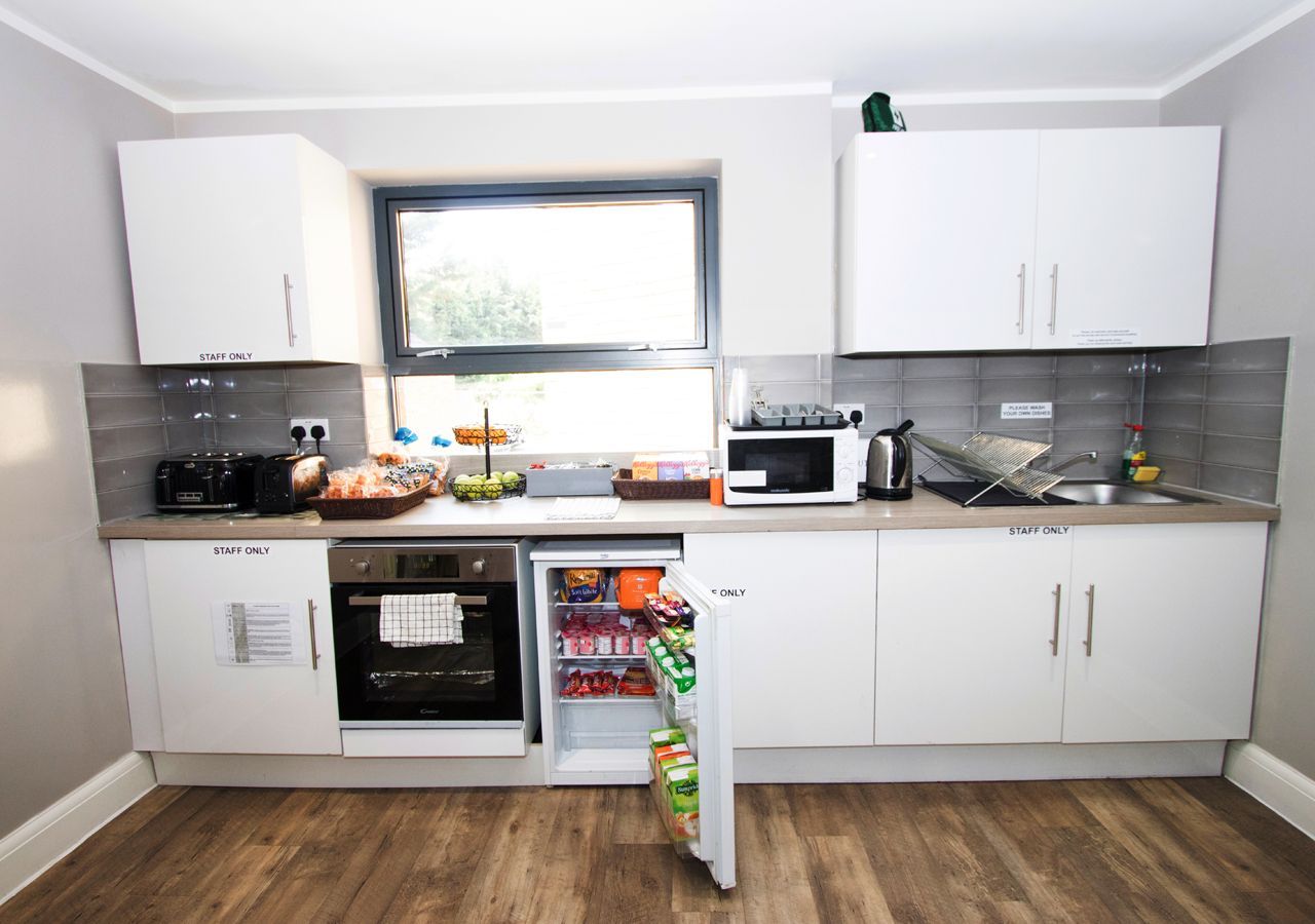 A kitchen with white cabinets and a small refrigerator