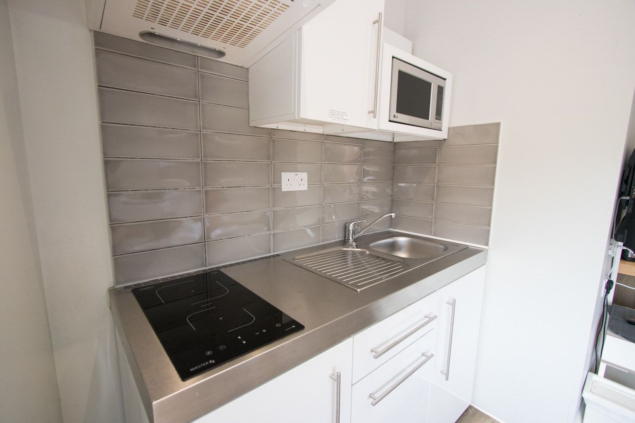 A small kitchen with a stove top oven , sink , and microwave.