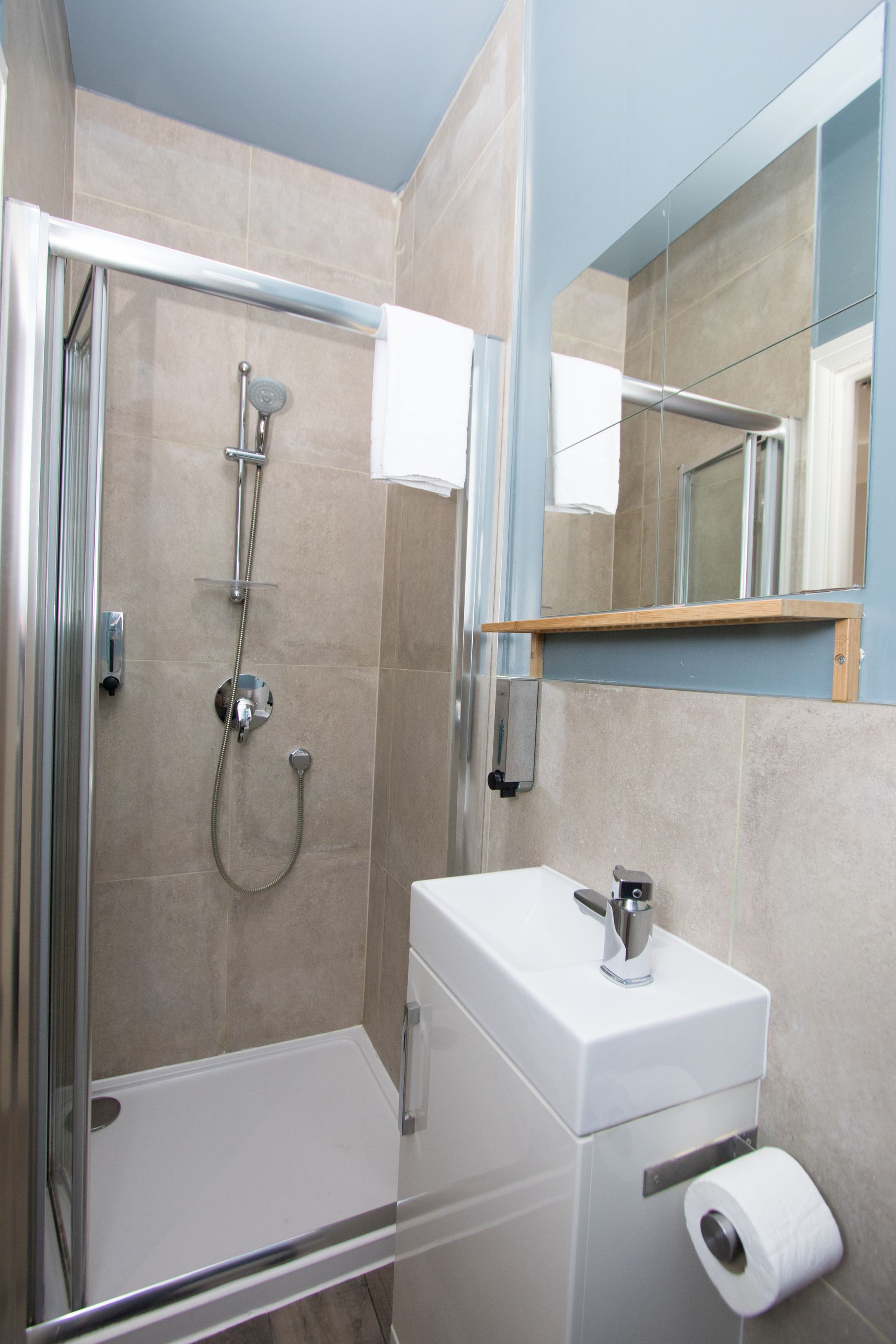 A bathroom with a shower , sink and mirror