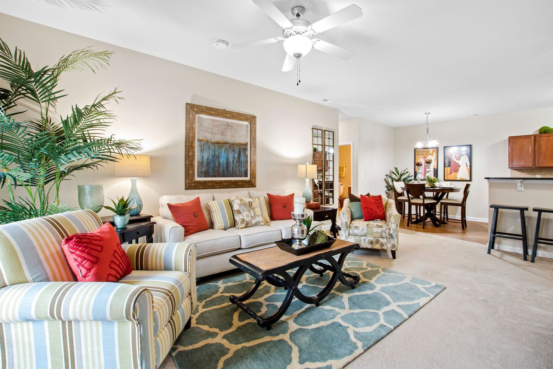 Bright living room in an open-plan apartment with sofa, chairs, and a dining area.