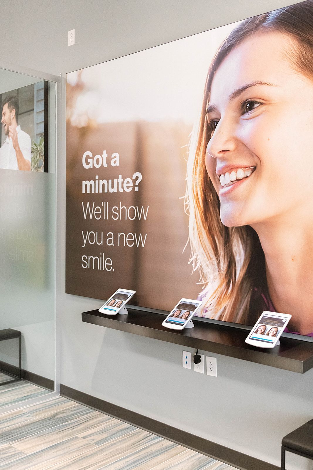 Waiting area with dental advertisement. Smiling person with white teeth on the poster. Four phones on a shelf.