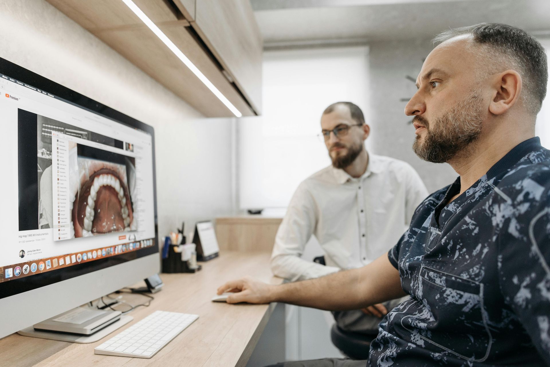 Dentist showing teeth scan on monitor to a colleague in office.