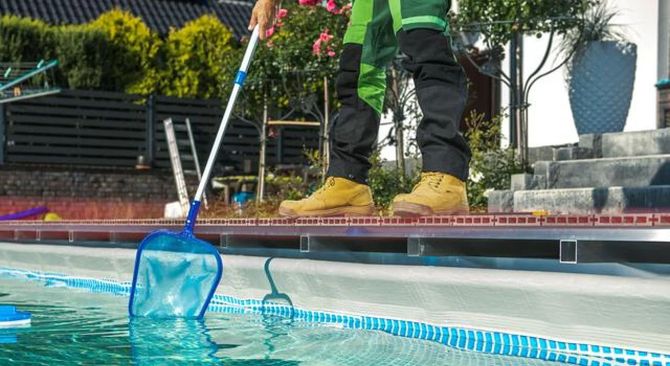 Pool cleaner skimming debris from a swimming pool with a blue net