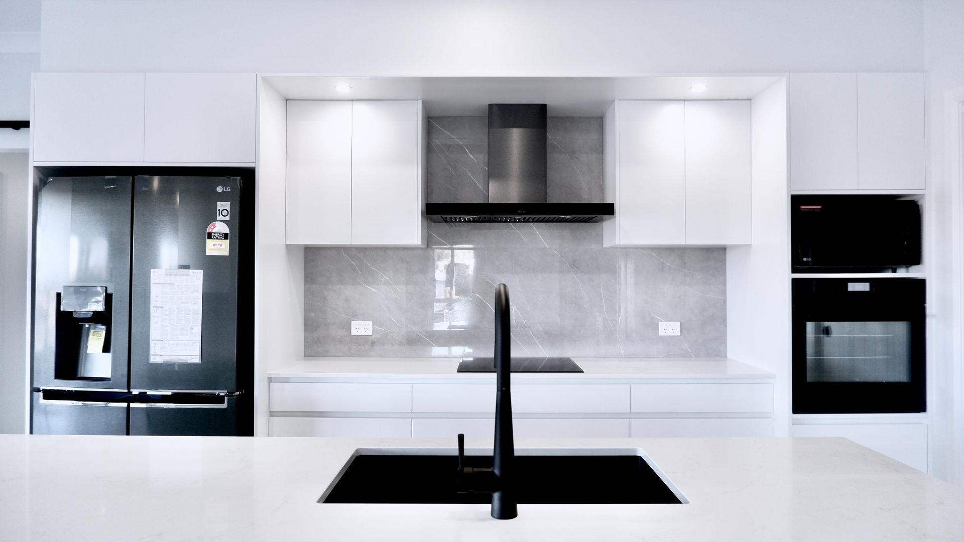 A kitchen with white cabinets , black appliances and a black sink.