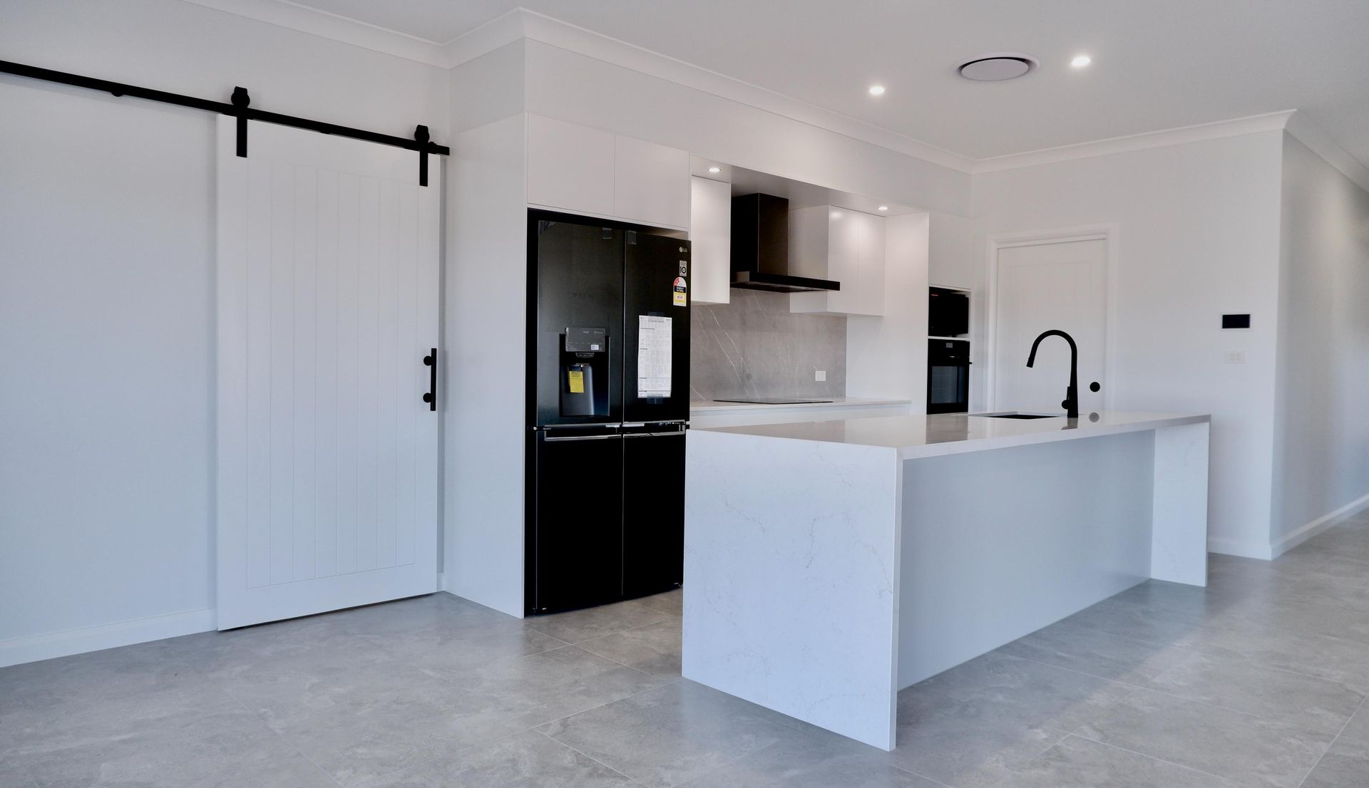 An empty kitchen with black appliances and white cabinets