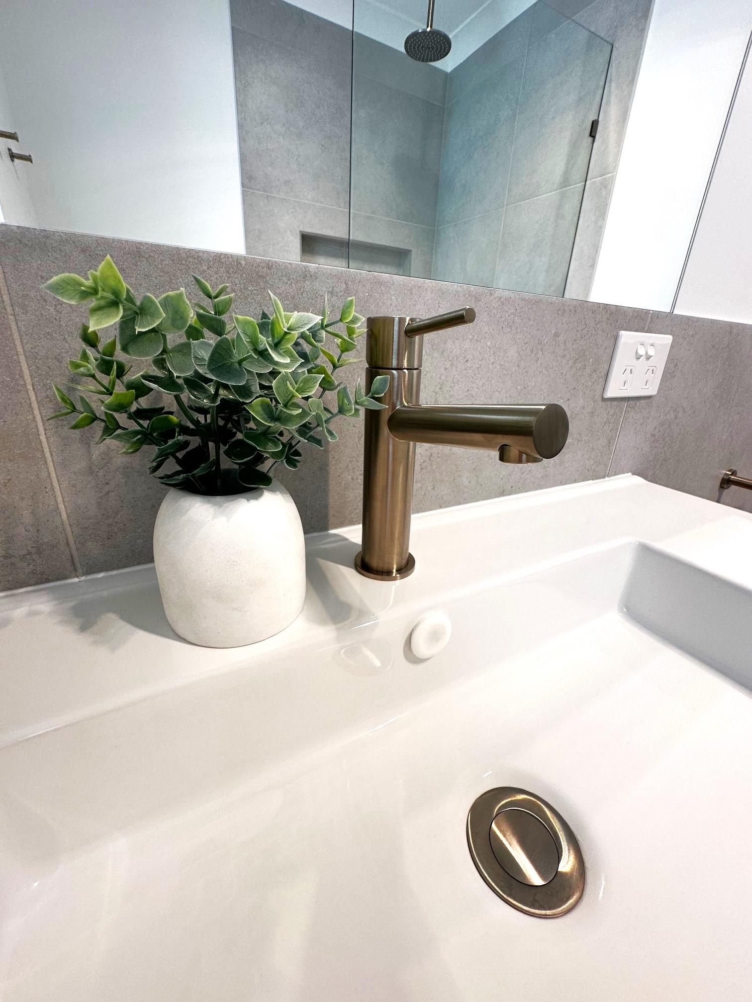 A bathroom sink with a plant in a pot on top of it.