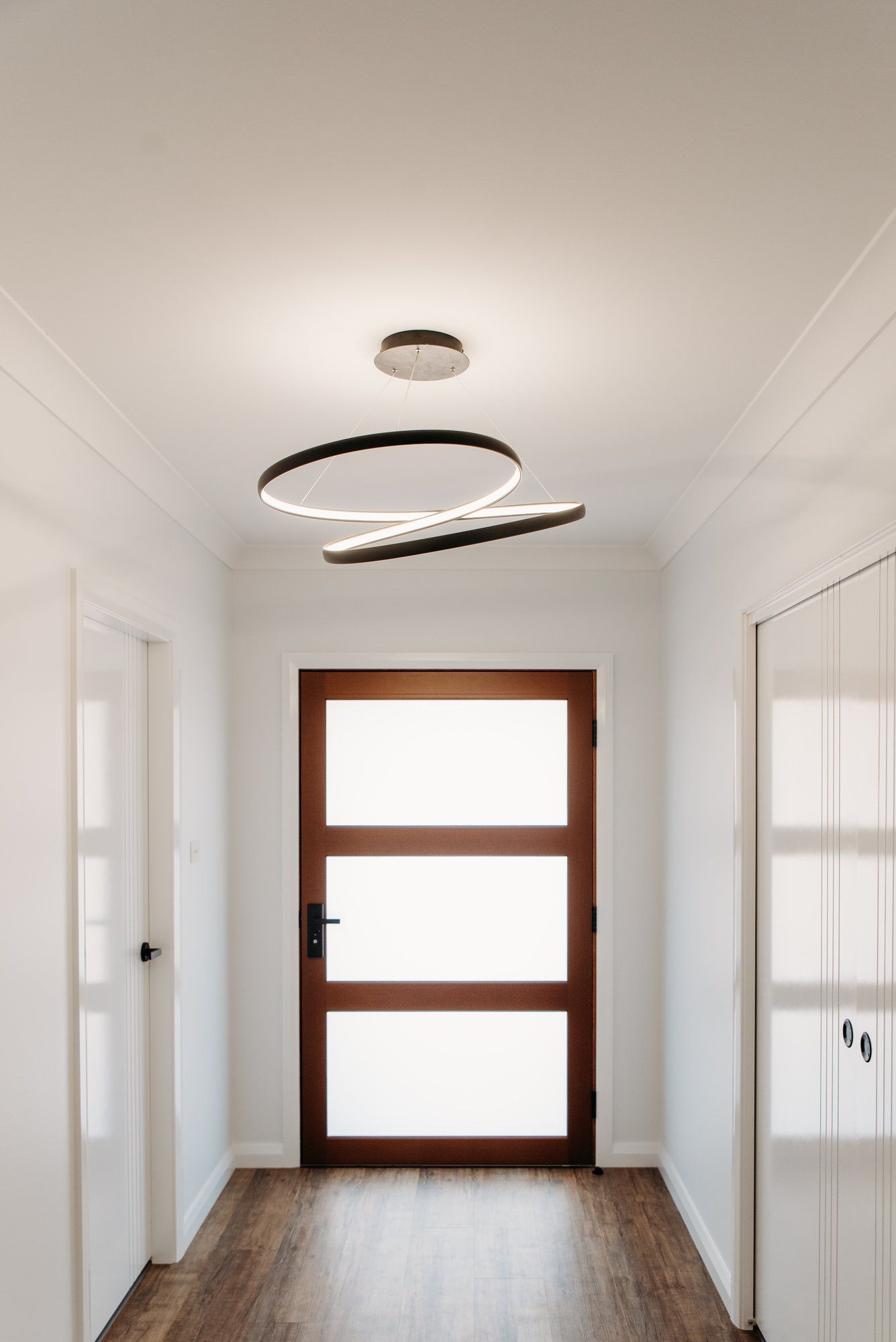 A hallway with a wooden door and a ceiling light.