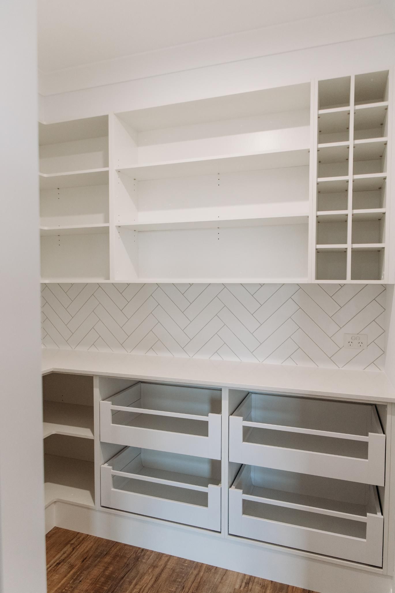 A closet with lots of shelves and drawers and a wooden floor.