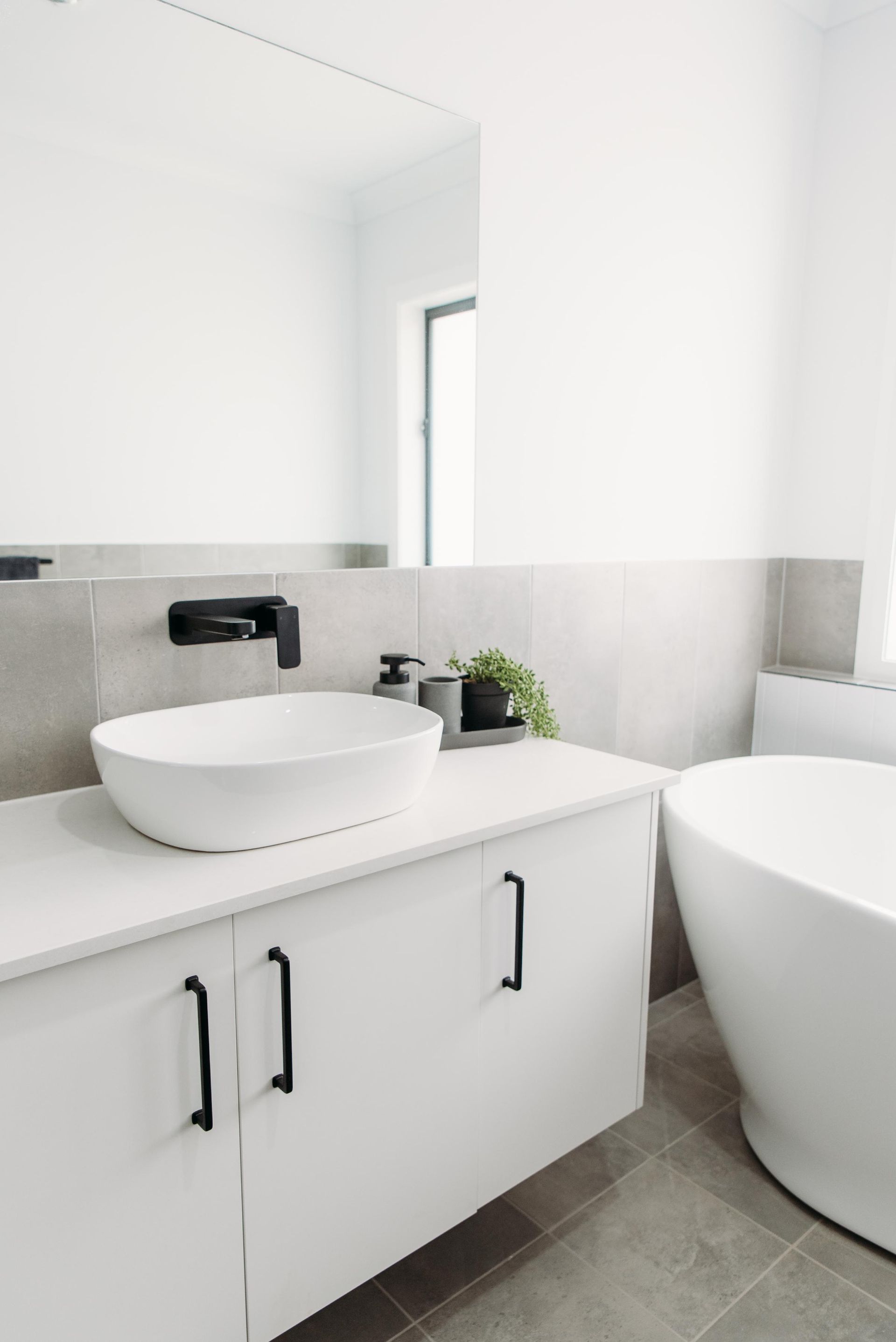 A bathroom with a sink , tub and mirror.