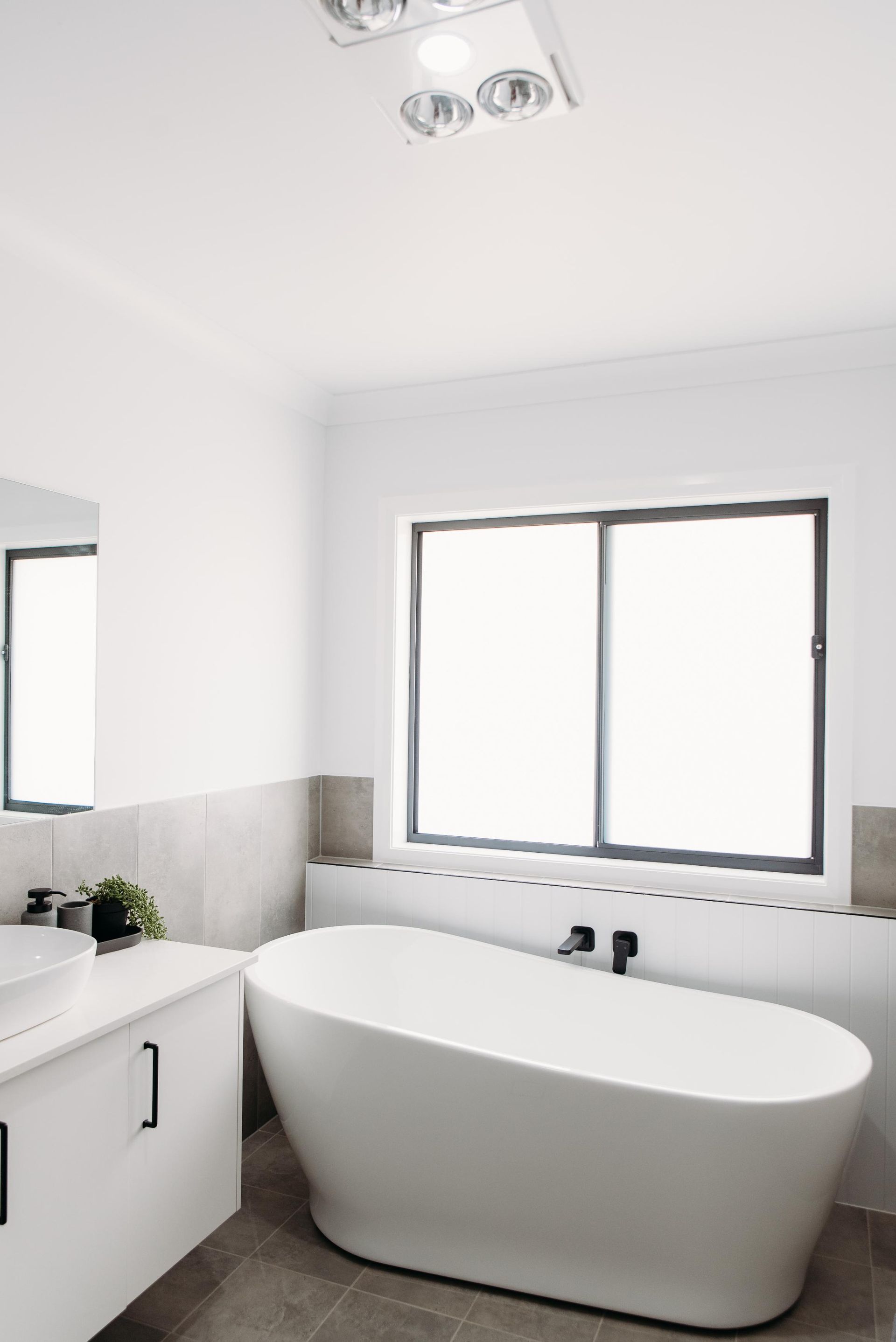 A bathroom with a bathtub , sink , mirror and window.