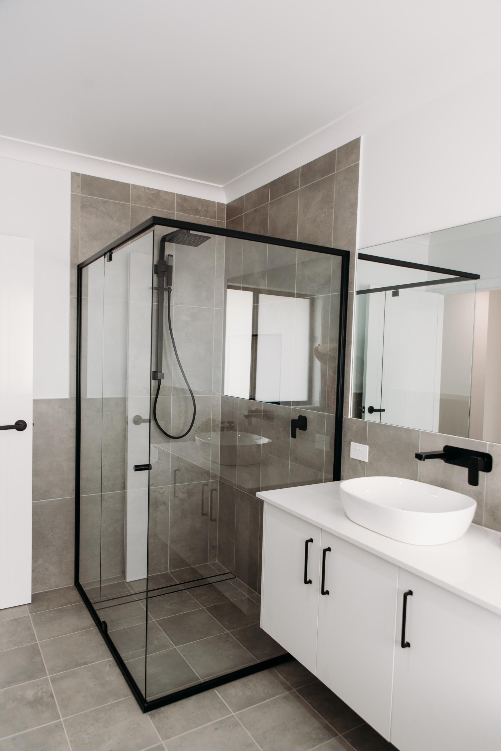 A bathroom with a shower , sink and mirror.