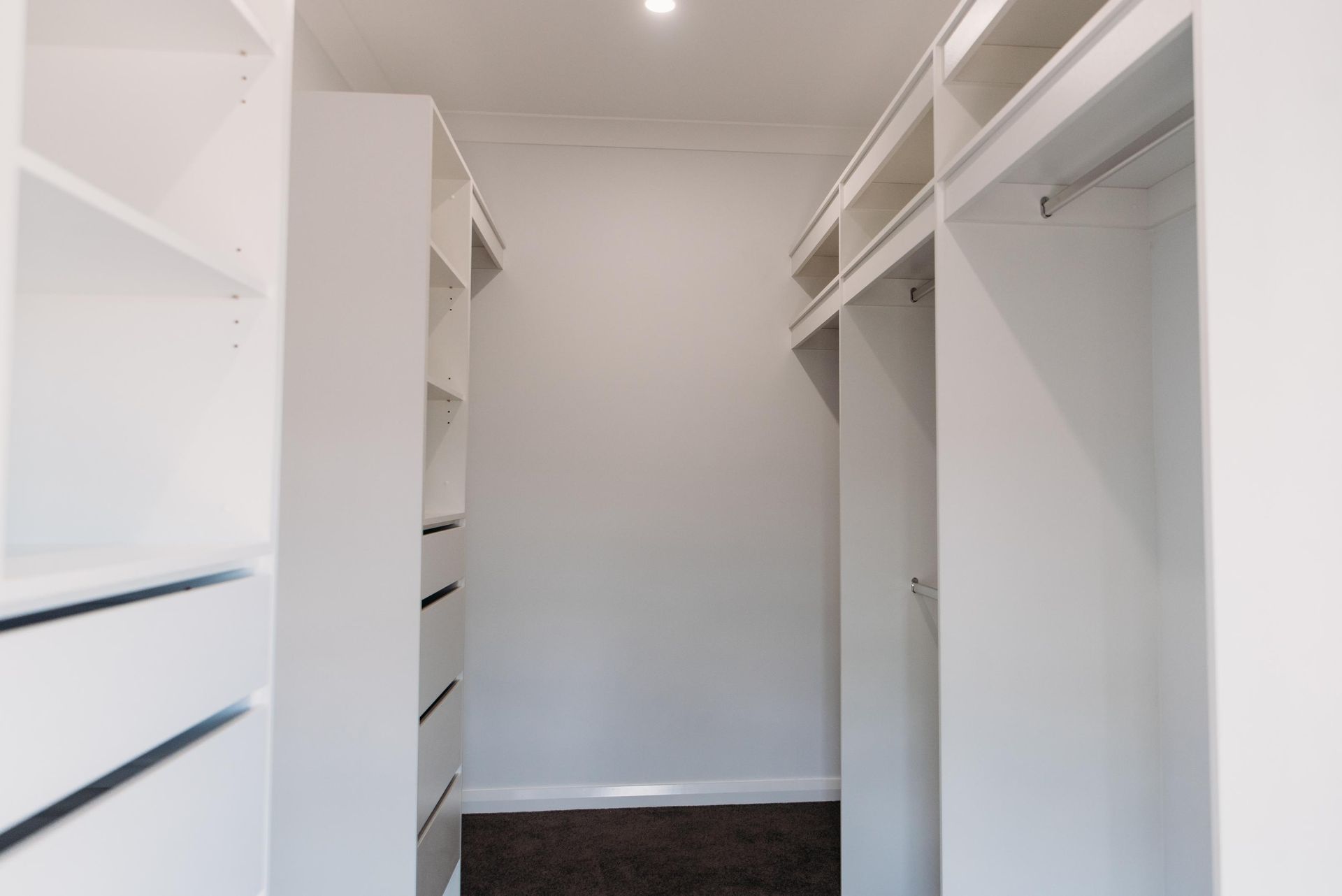 A walk in closet with lots of shelves and drawers.