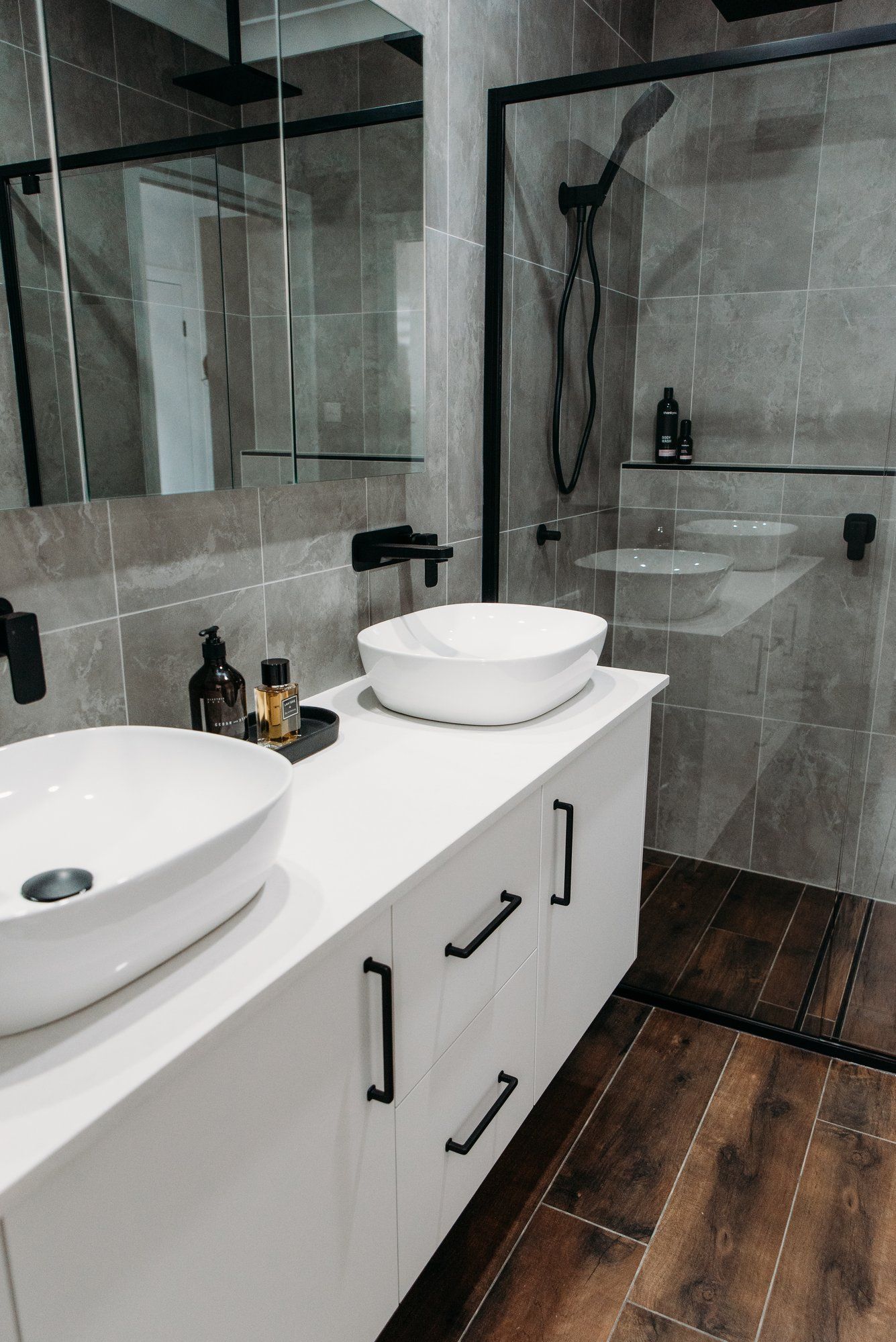 A bathroom with two sinks and a walk in shower.