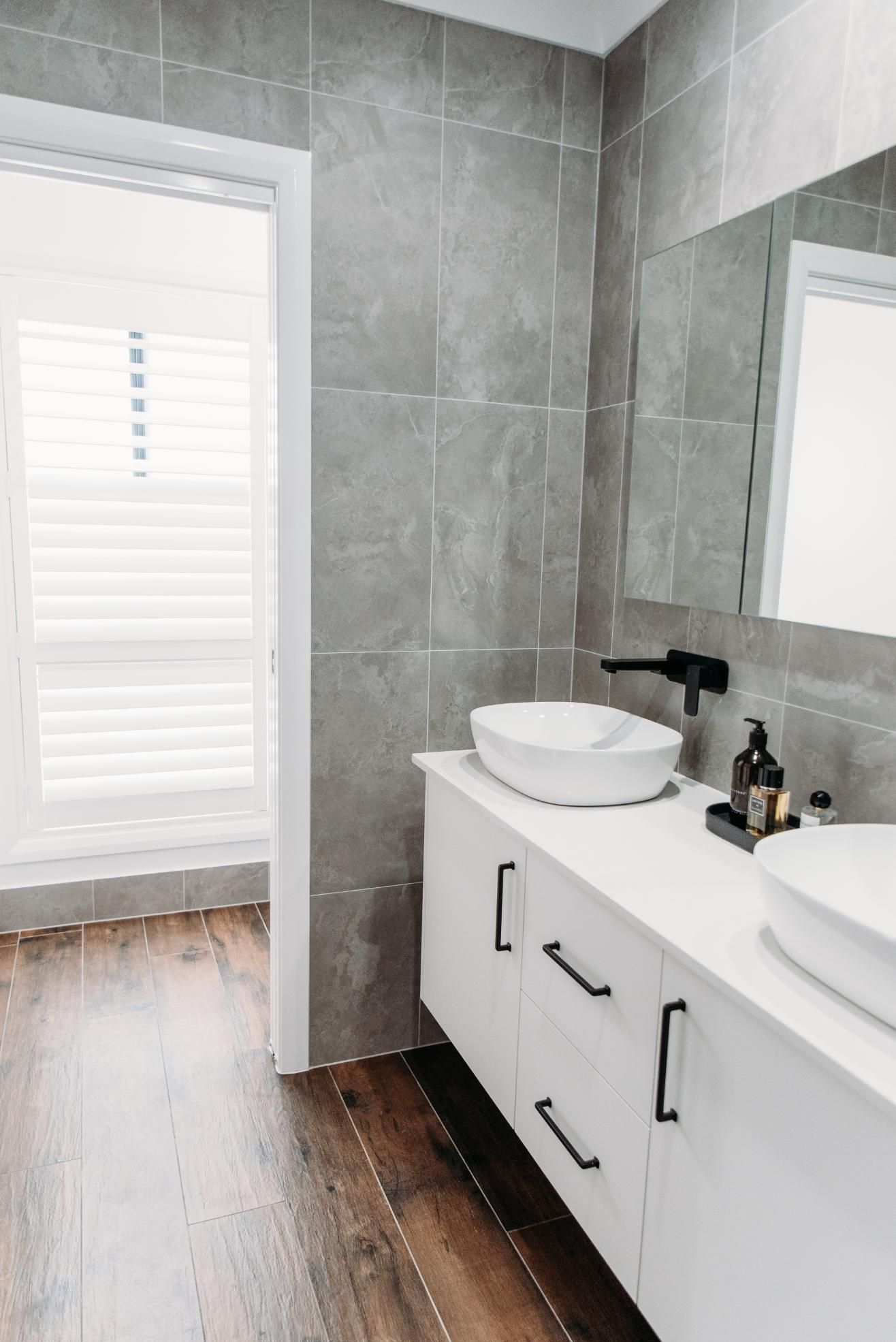 A bathroom with two sinks , a mirror and a window.