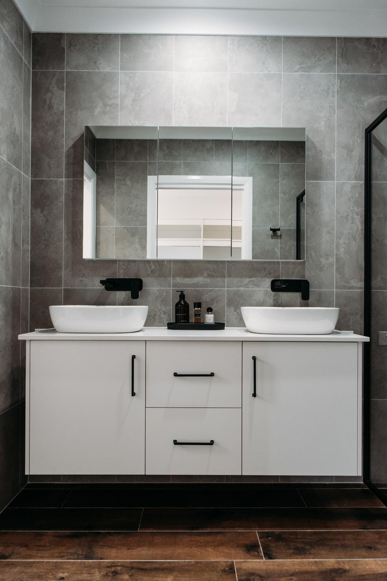 A bathroom with two sinks , a mirror and a wooden floor.