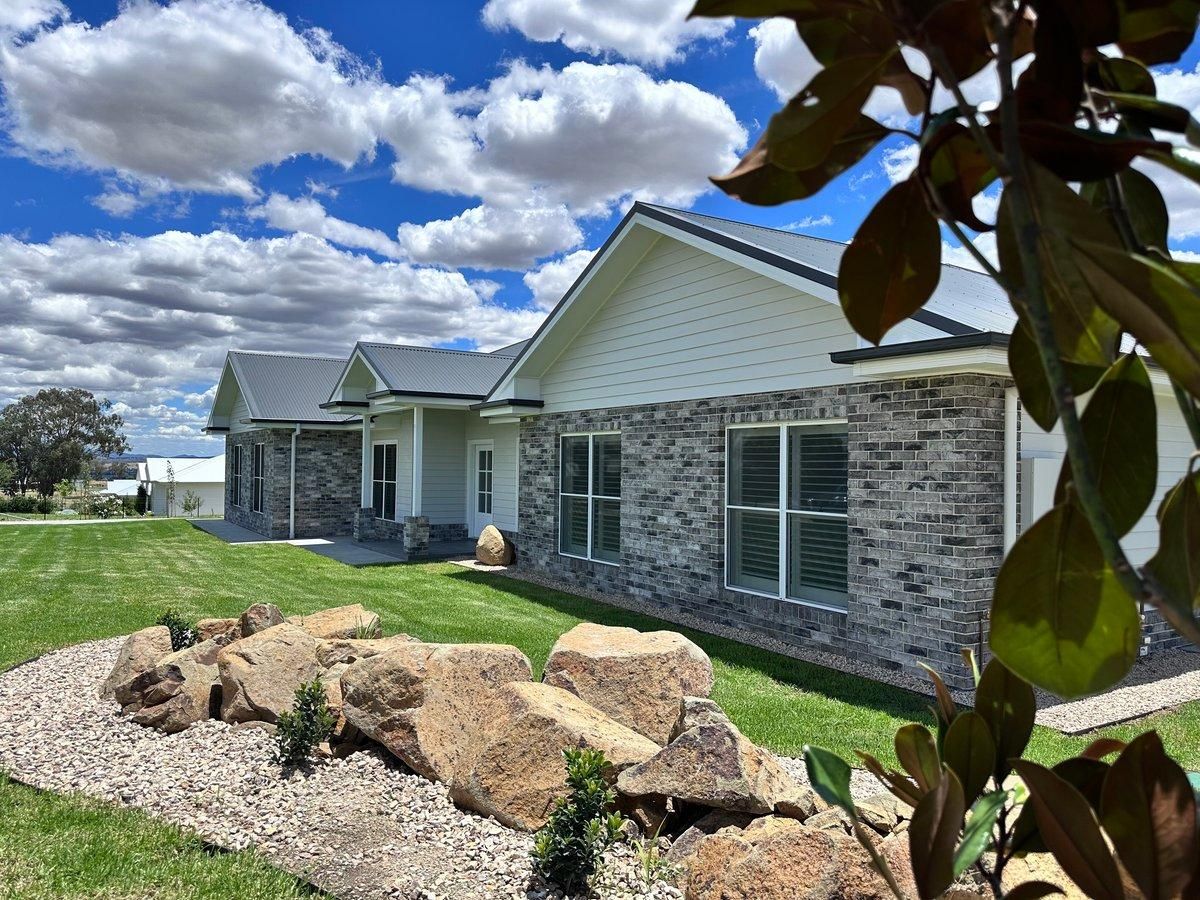 A house with a lot of windows and a lot of rocks in front of it.