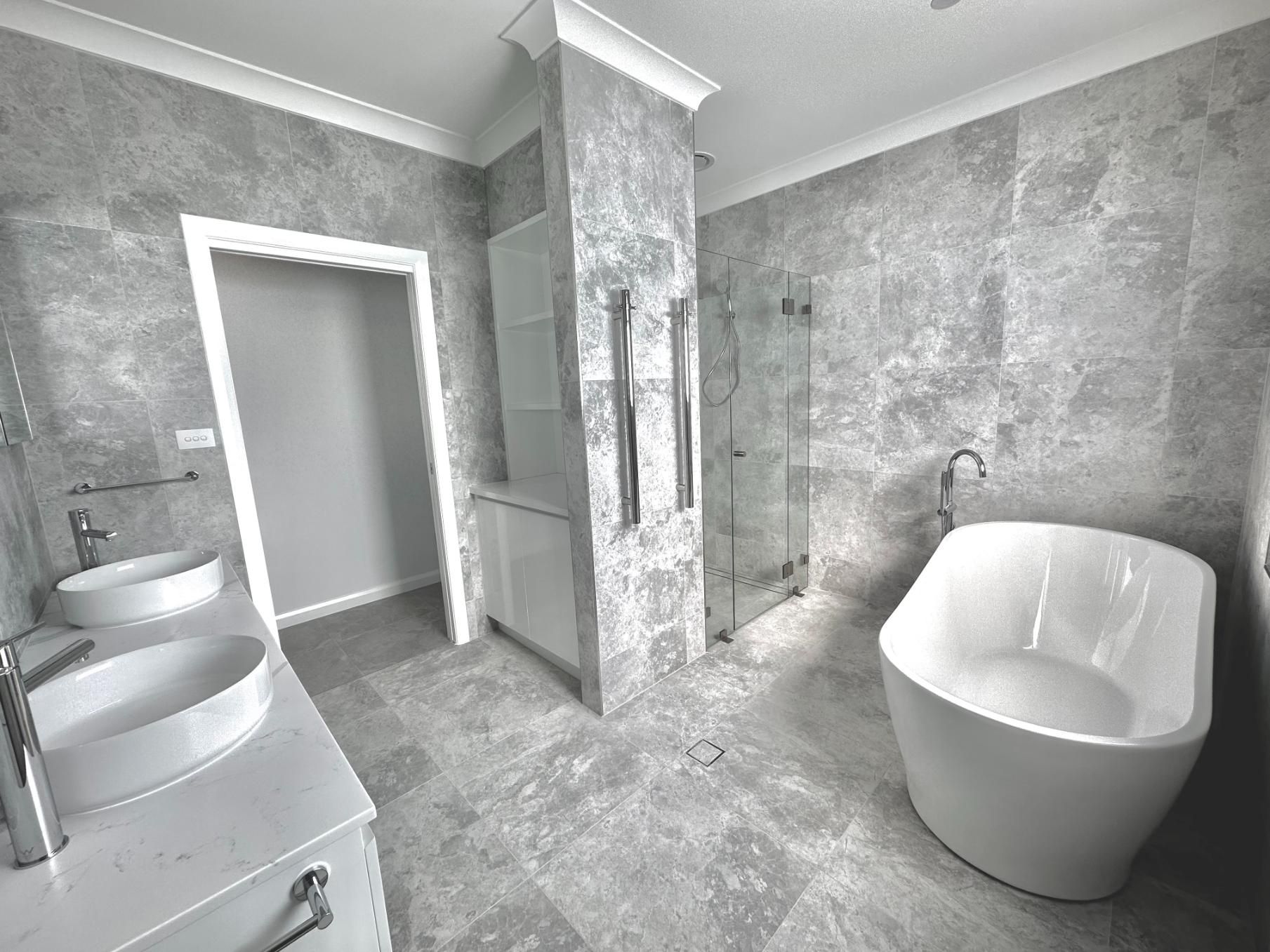 A bathroom with two sinks , a tub , and a shower.