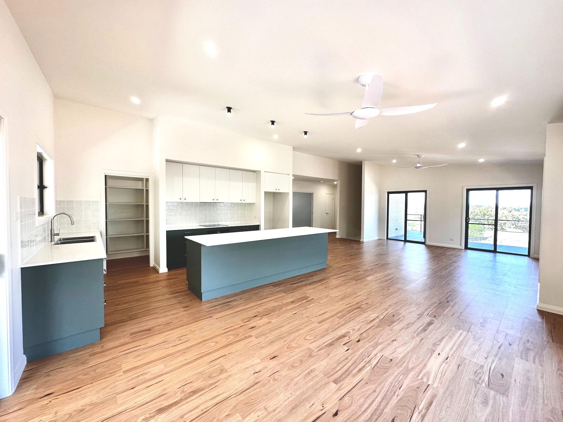 A large empty room with hardwood floors and a kitchen.