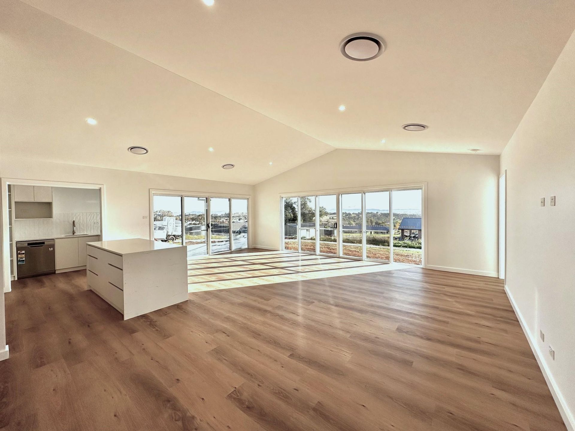 A large empty room with hardwood floors and lots of windows.