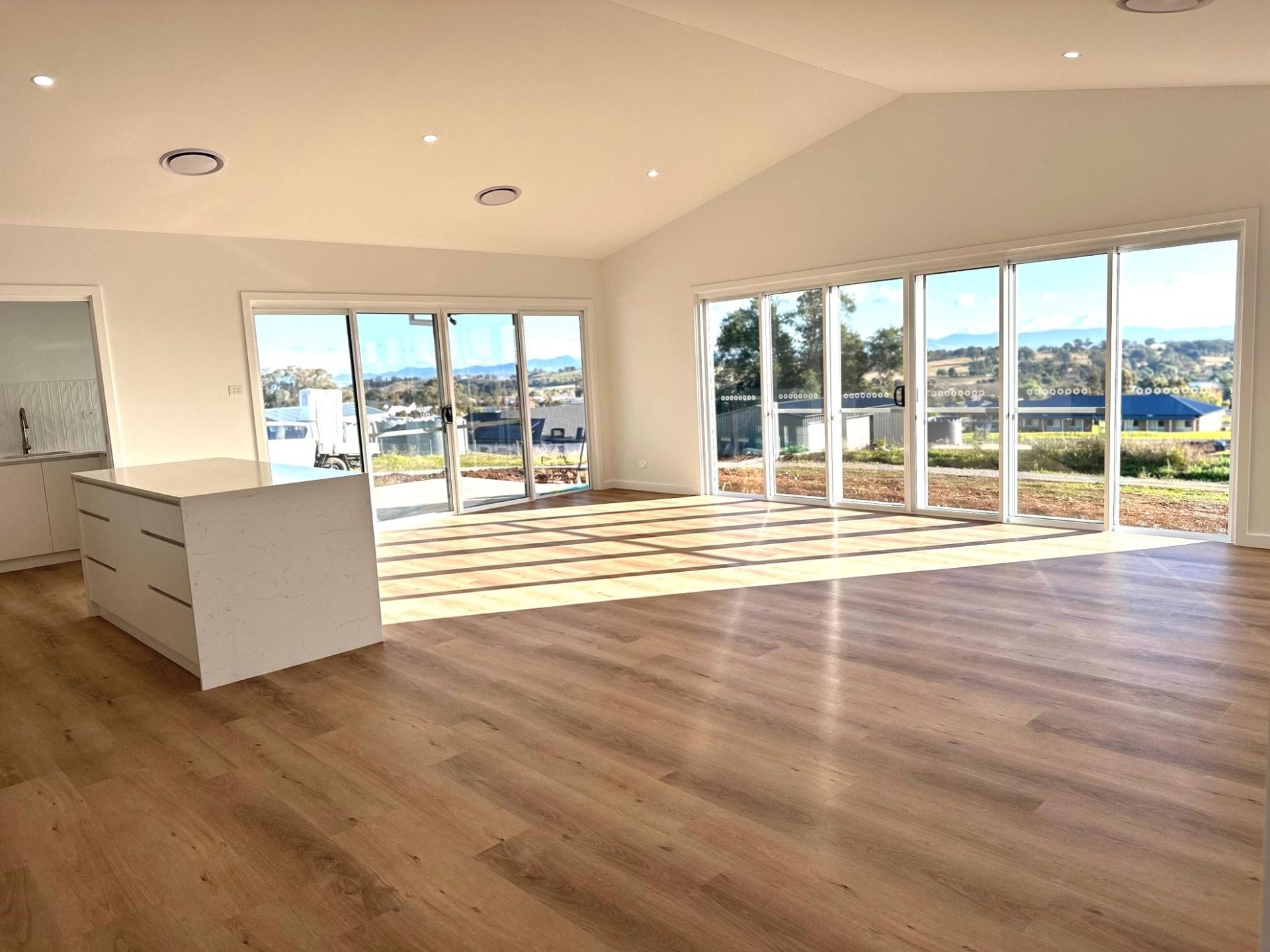 An empty living room with hardwood floors and lots of windows.