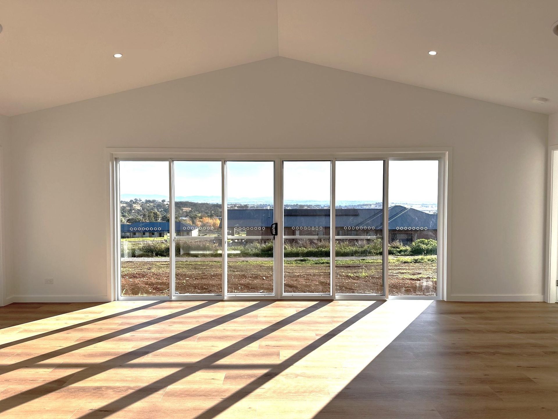 An empty room with a lot of windows and a wooden floor.
