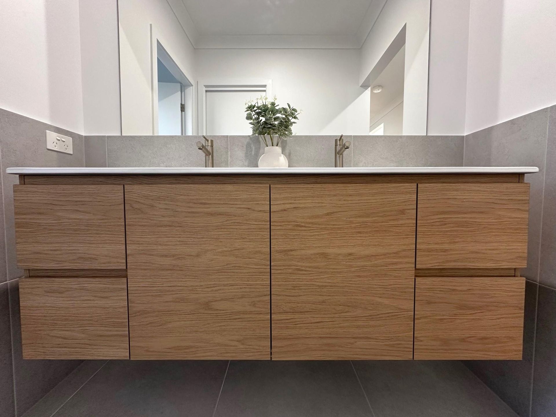 A bathroom with two sinks , a mirror and a wooden vanity.