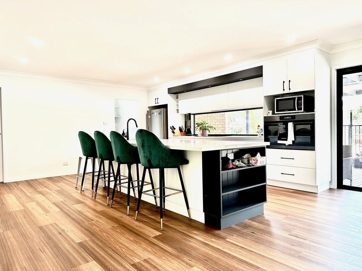A kitchen with a large island , stools , and a microwave.