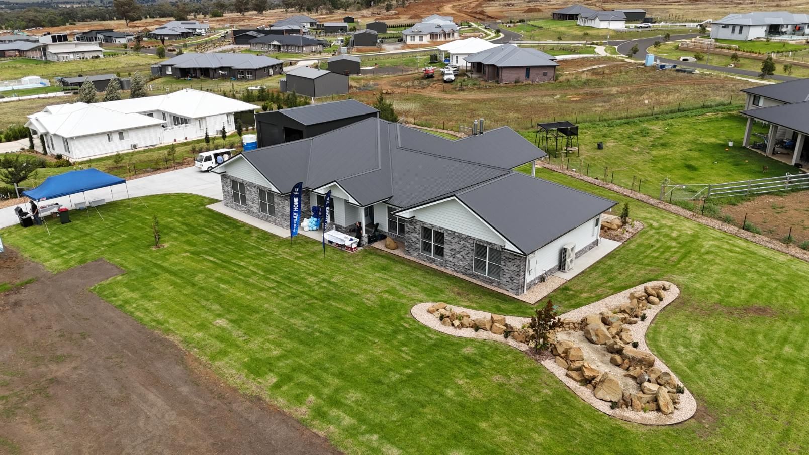 An aerial view of a house with a butterfly garden in front of it.