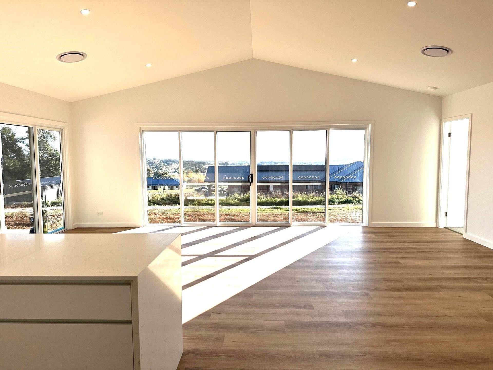 A large empty room with lots of windows and hardwood floors.