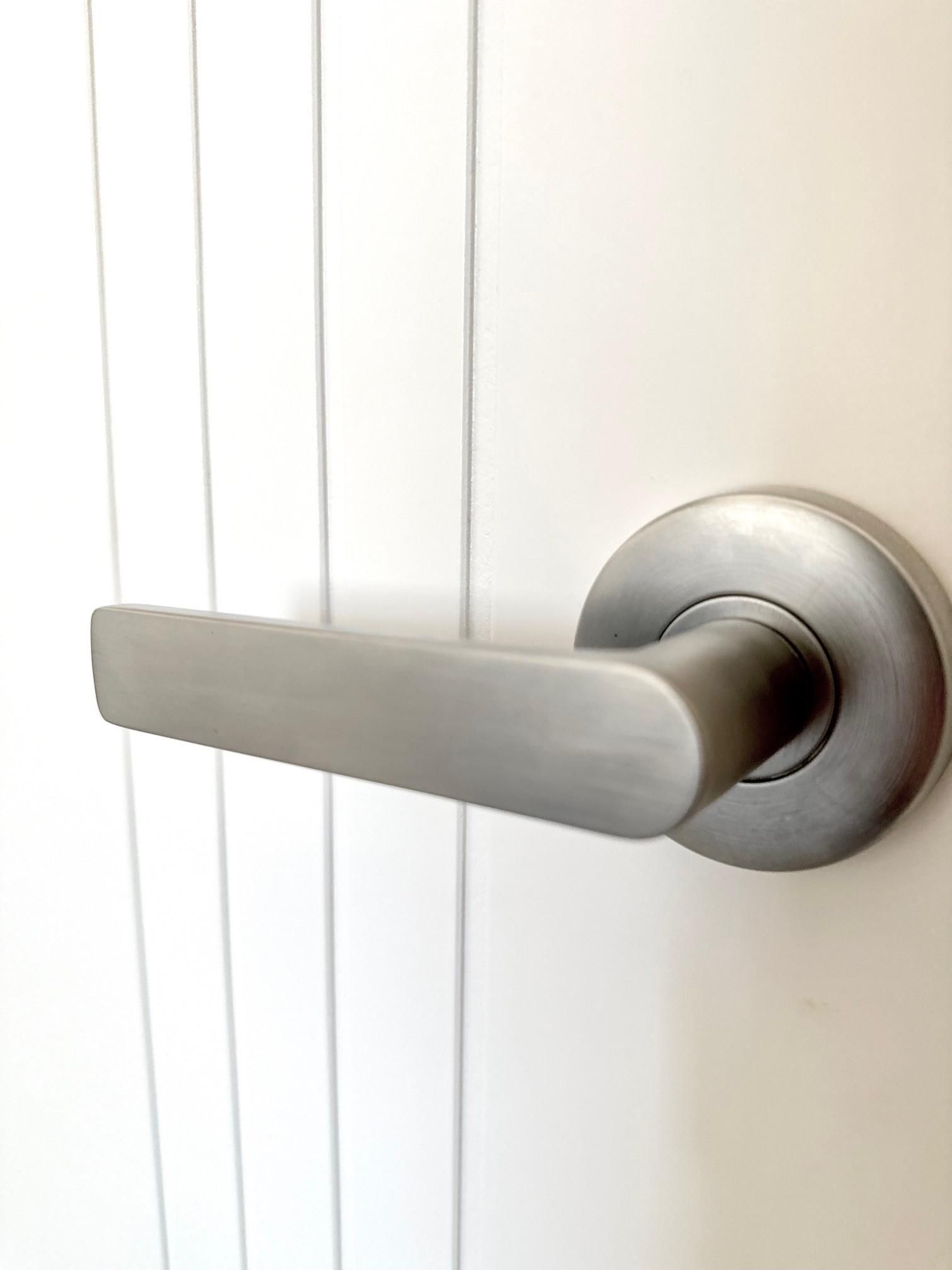 A close up of a door handle on a white door.