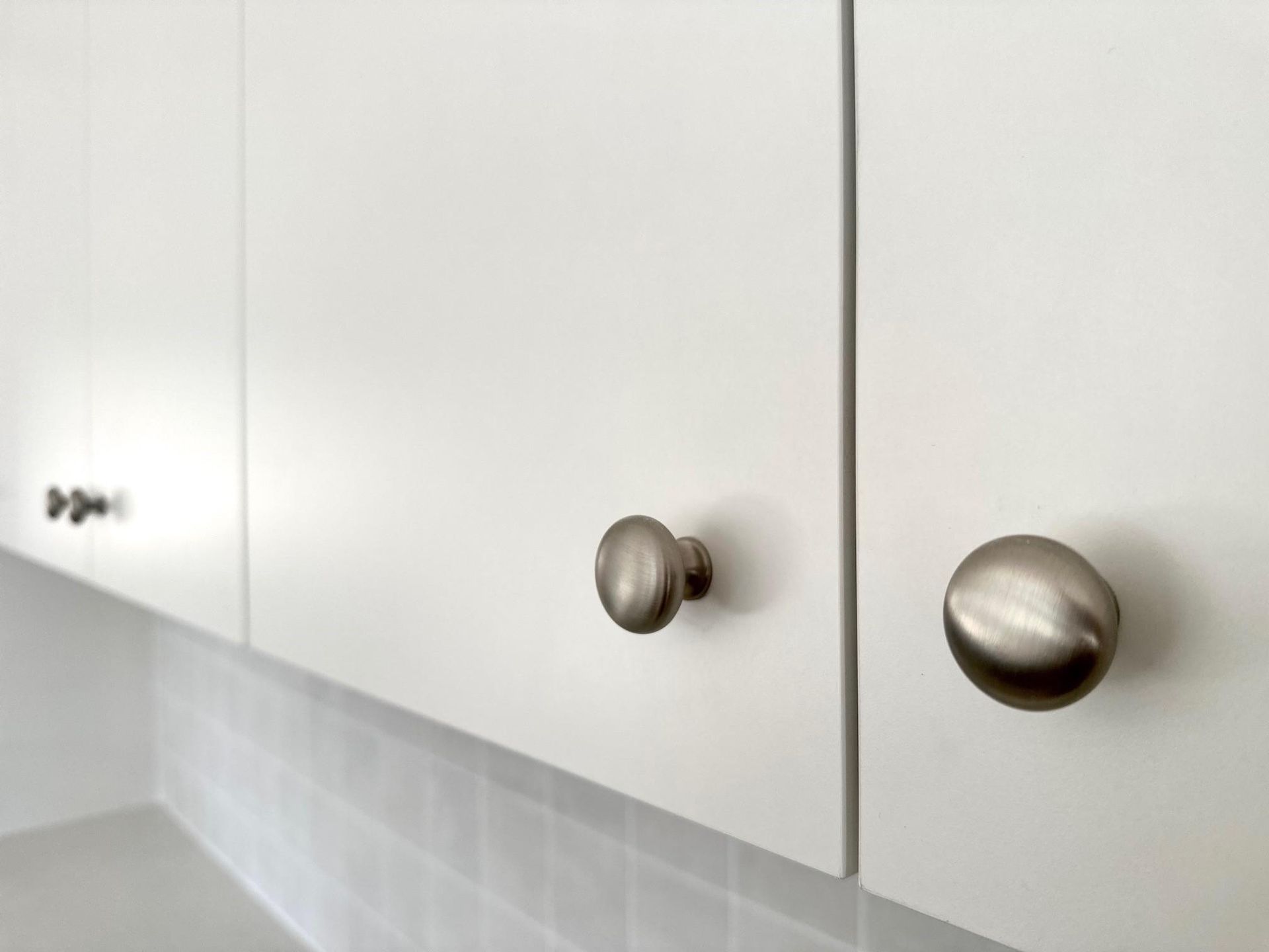 A close up of a kitchen cabinet with stainless steel knobs.