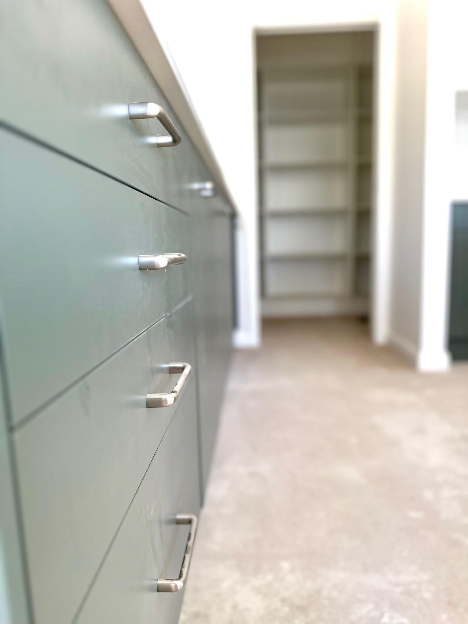 A row of drawers in a kitchen with a shelf in the background