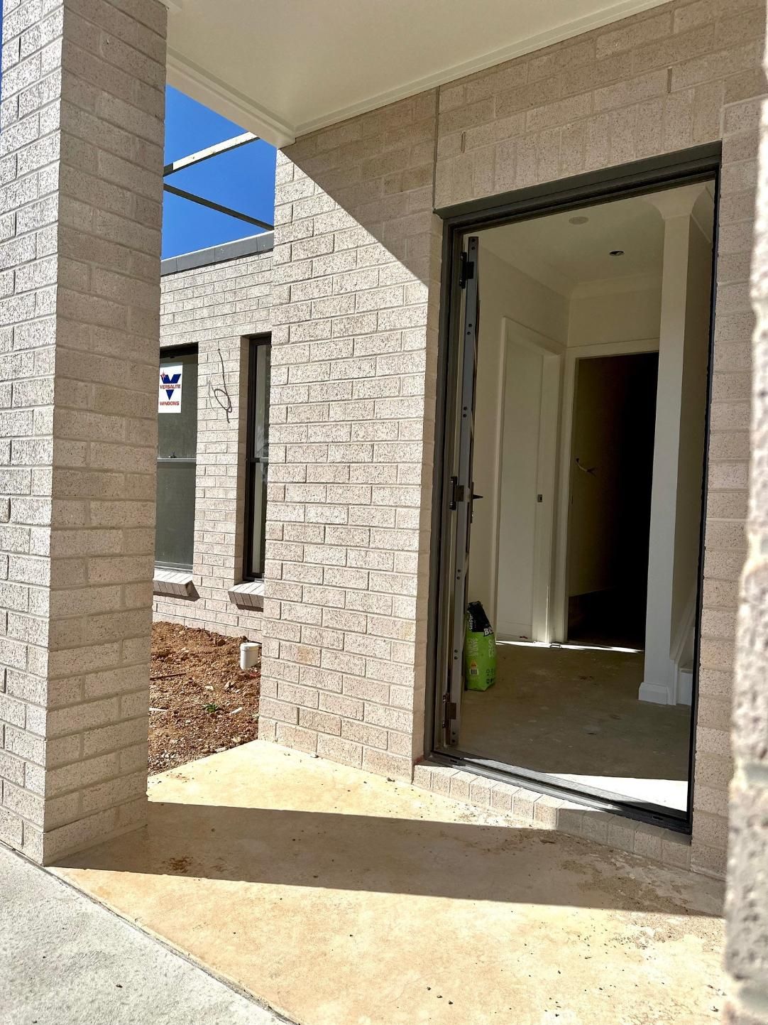 A brick building with a sliding glass door is under construction.