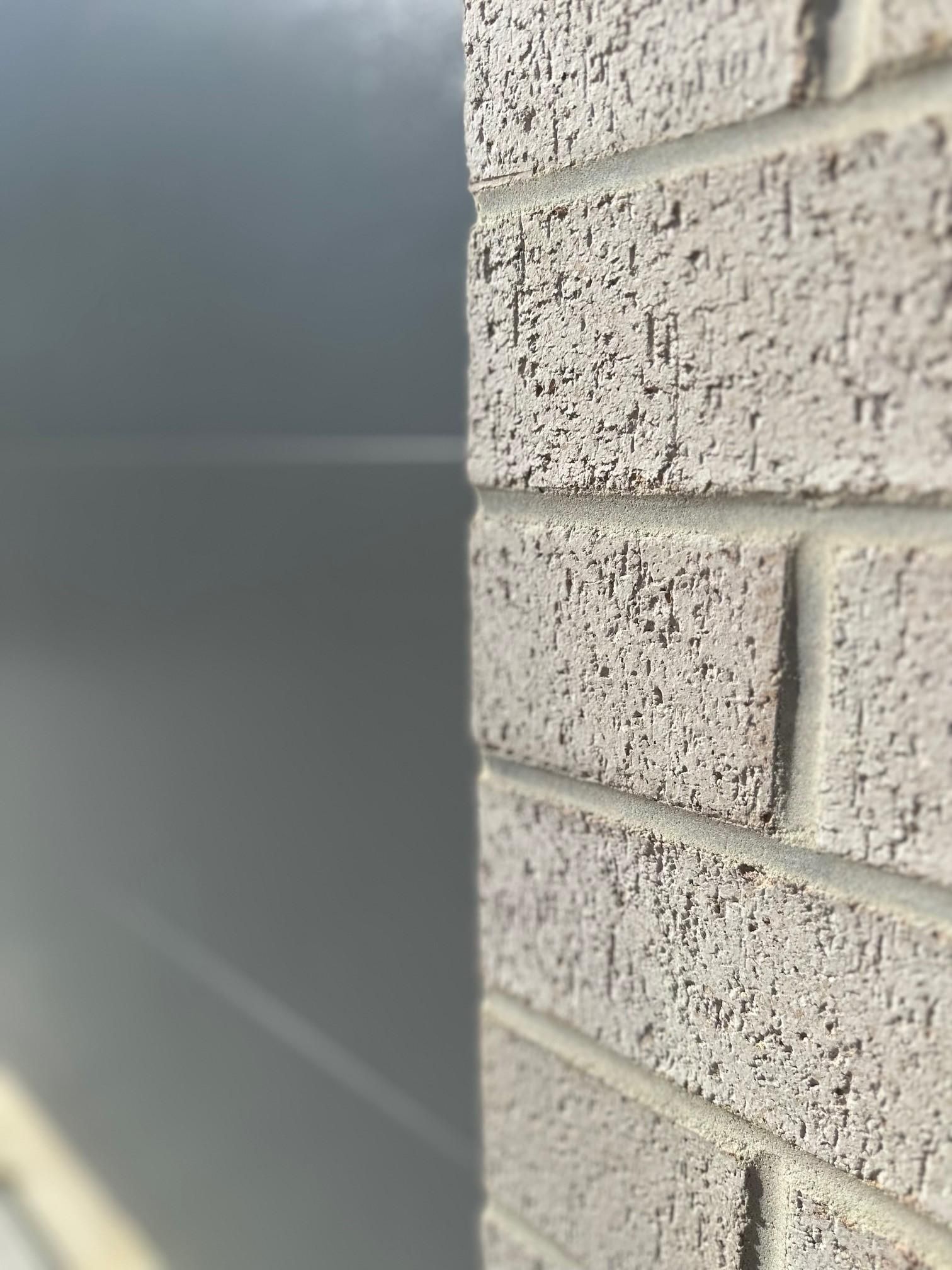 A close up of a brick wall with a car in the background.