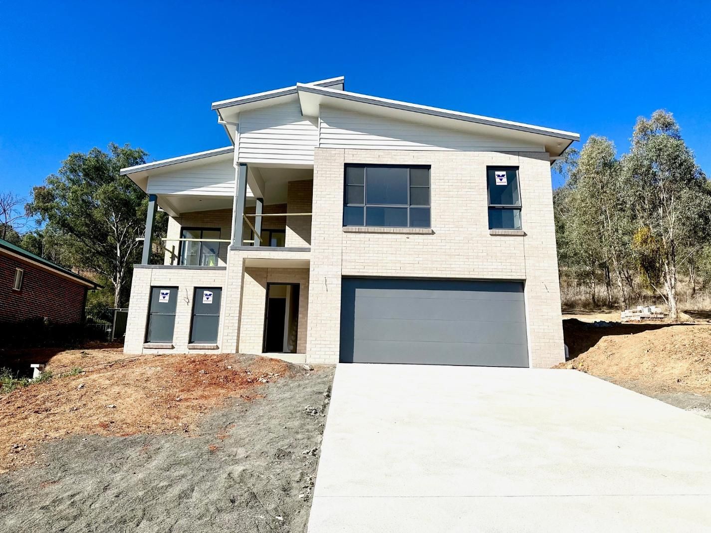 A large white house with a gray garage door is sitting on top of a hill.