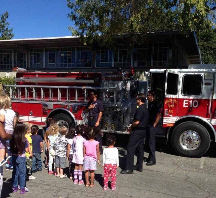 A group of children are standing in front of a fire truck that says e10