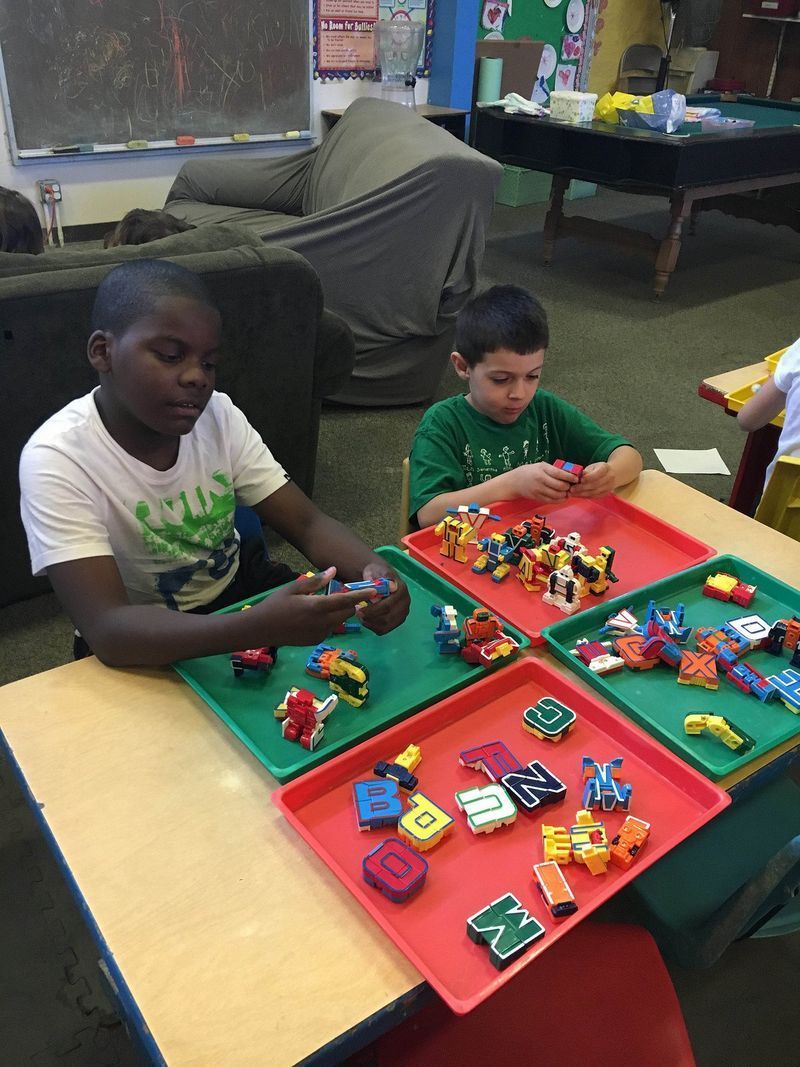 Two boys are sitting at a table playing with lego blocks