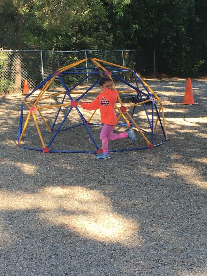 A little girl is playing in a playground with a dome.