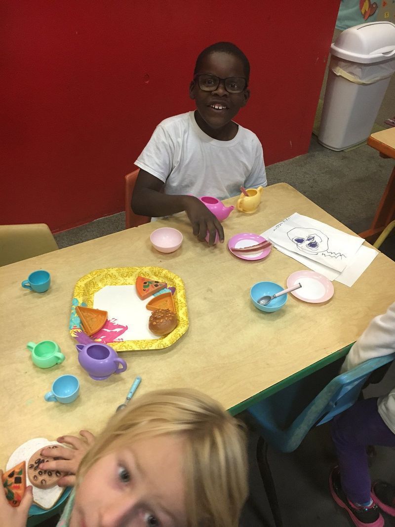 A boy and a girl are sitting at a table with toys on it