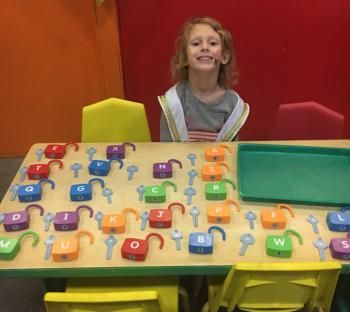 A little girl is sitting at a table with keys and locks on it.